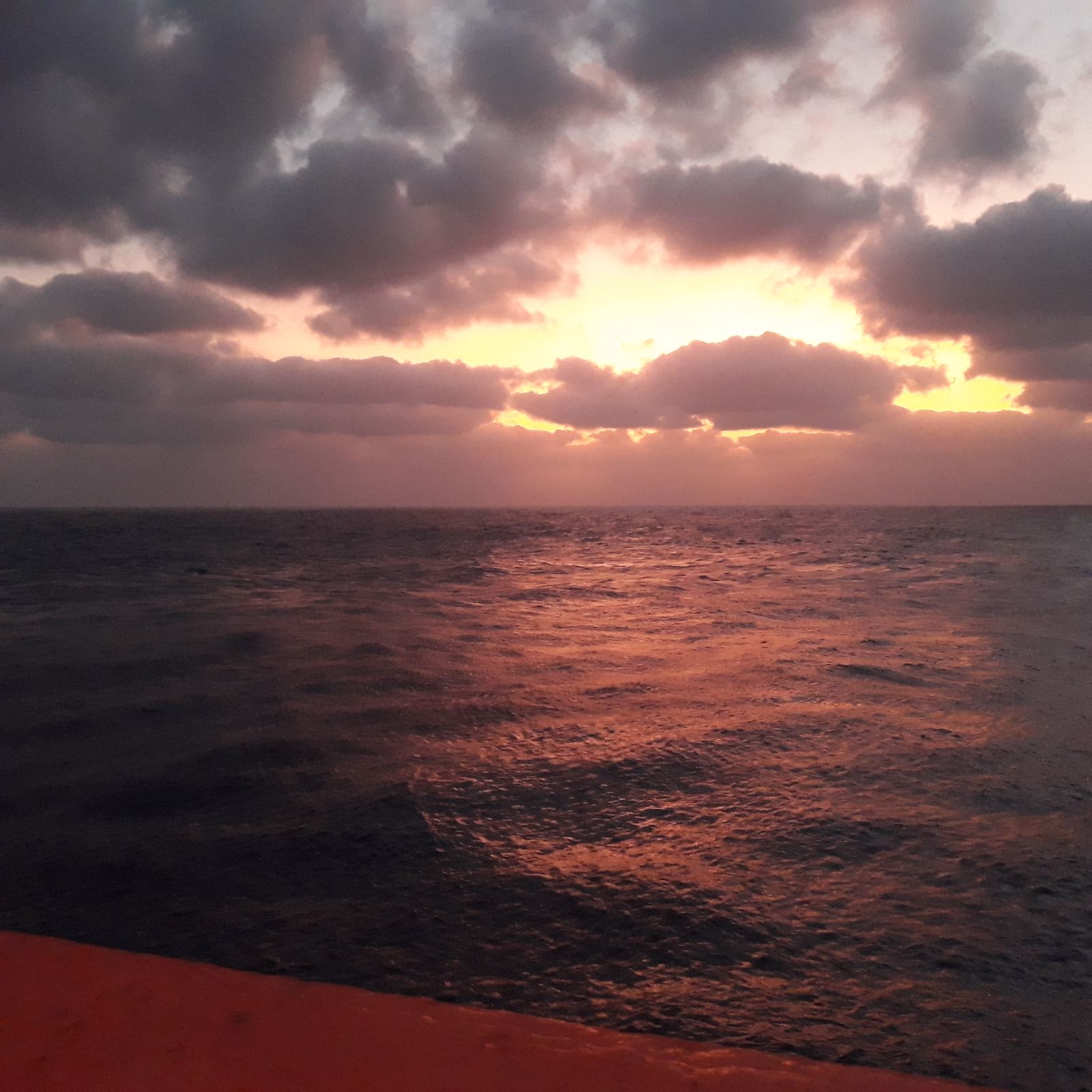 Sunset over the sea from a vessel deck